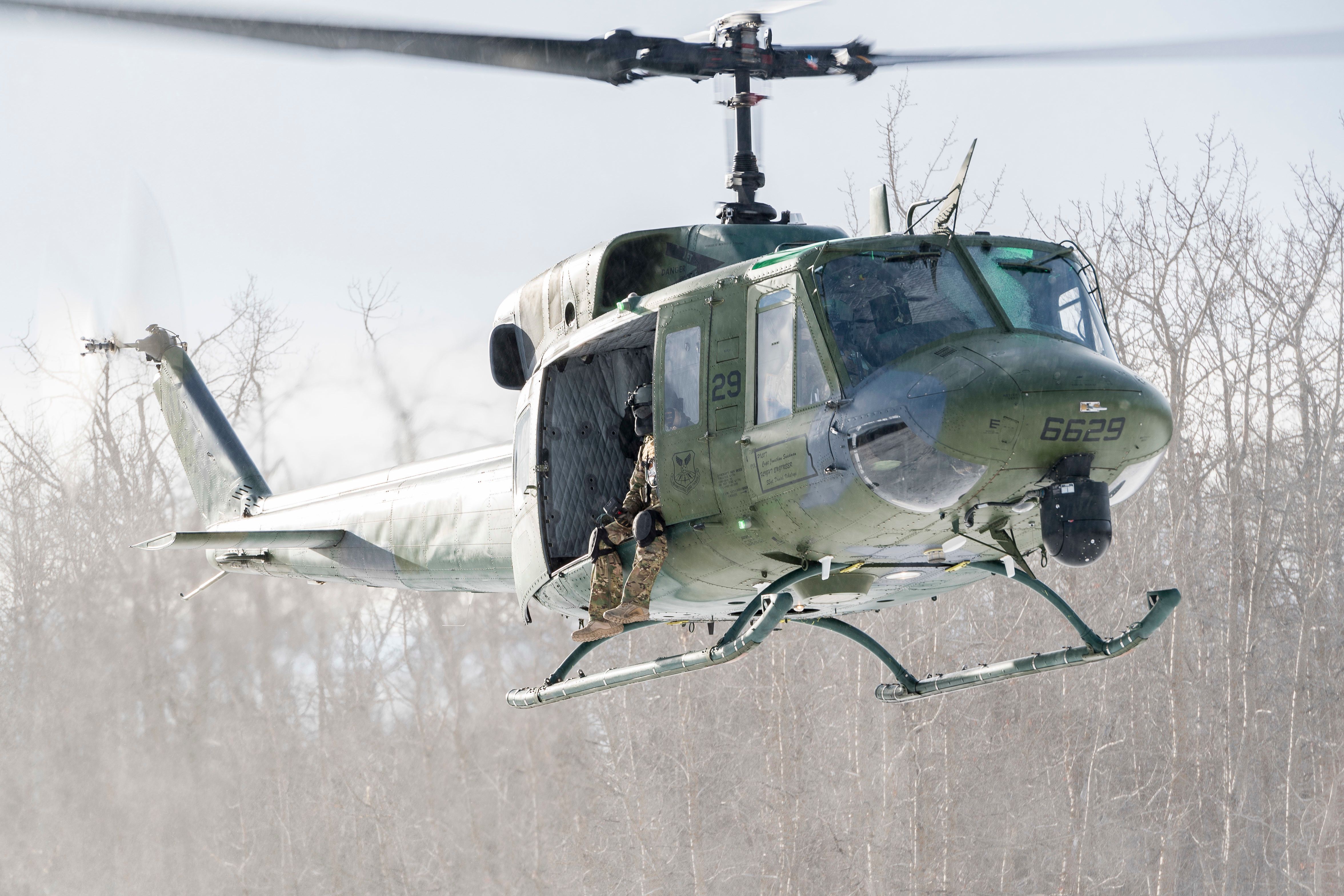 Photo of soldier sitting on the edge of a UH-1 Huey in flight