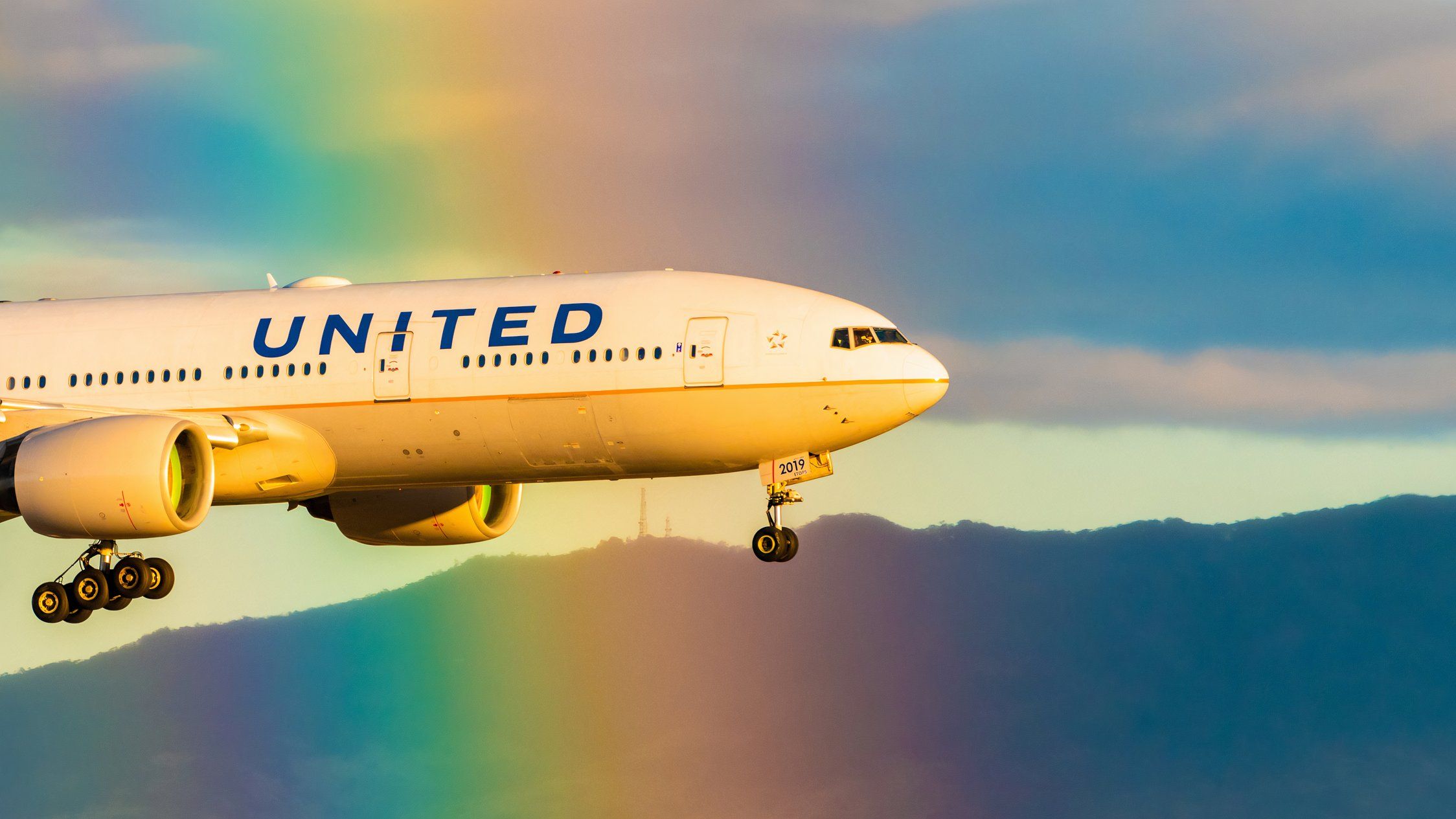 United Airlines Boeing 777-222 ER Registered N219UA flying through a rainbow PC shutterstock_1397936222 (2)