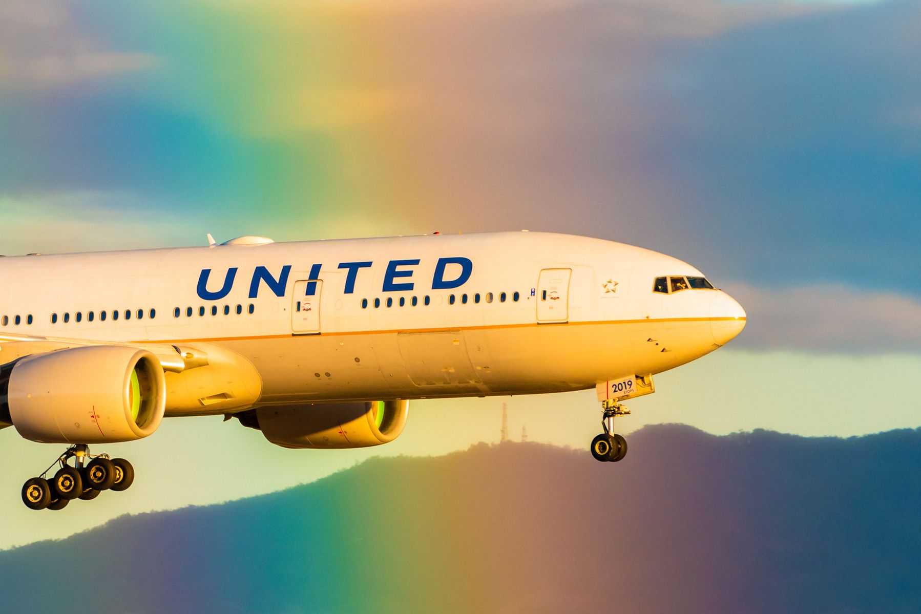 United Airlines Boeing 777 flying through a rainbow, close-up 3:2 Photo shutterstock