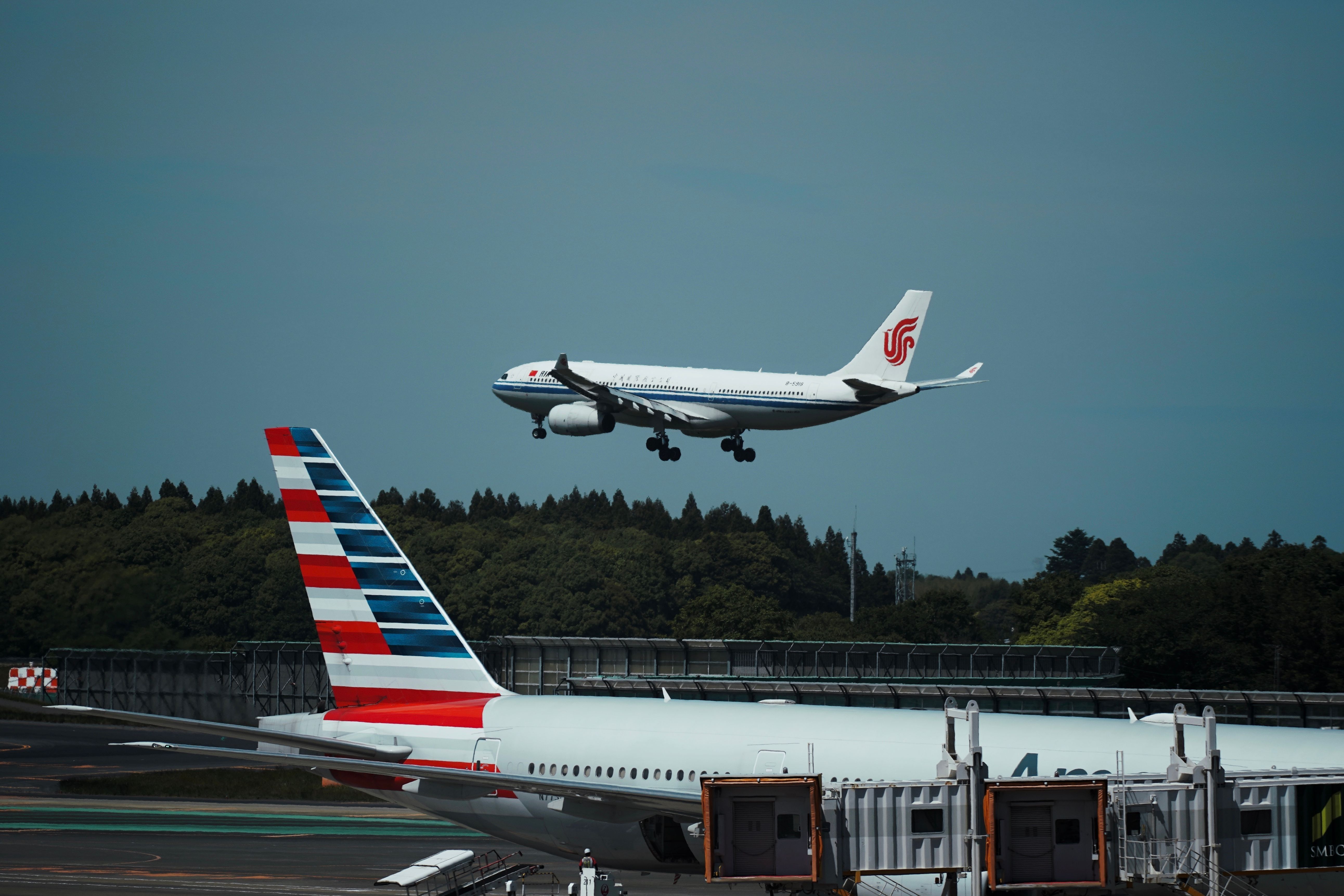 Airbus A330 of Air China landing, in the foreground an aircraft of American Airlines shutterstock_2417007465