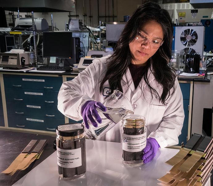 Materials, process & physics engineer Carissa Pajel pours the jet reference fluid into jar for sealants immersion testing in a laboratory