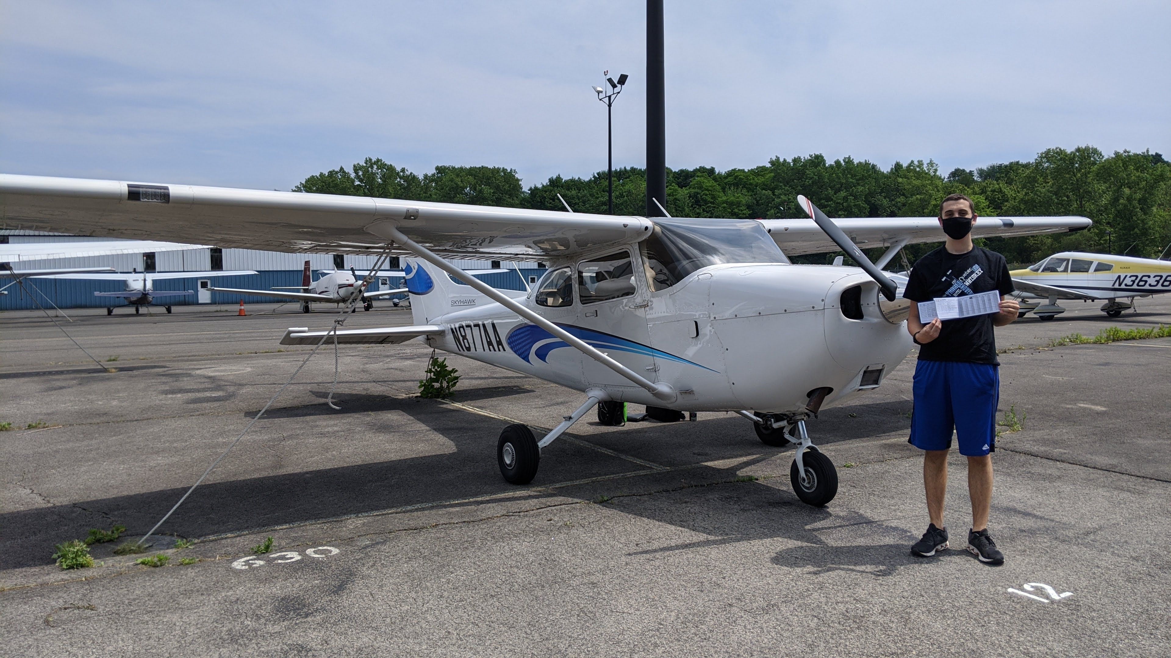 Me holding up my logbook after my first solo flight.