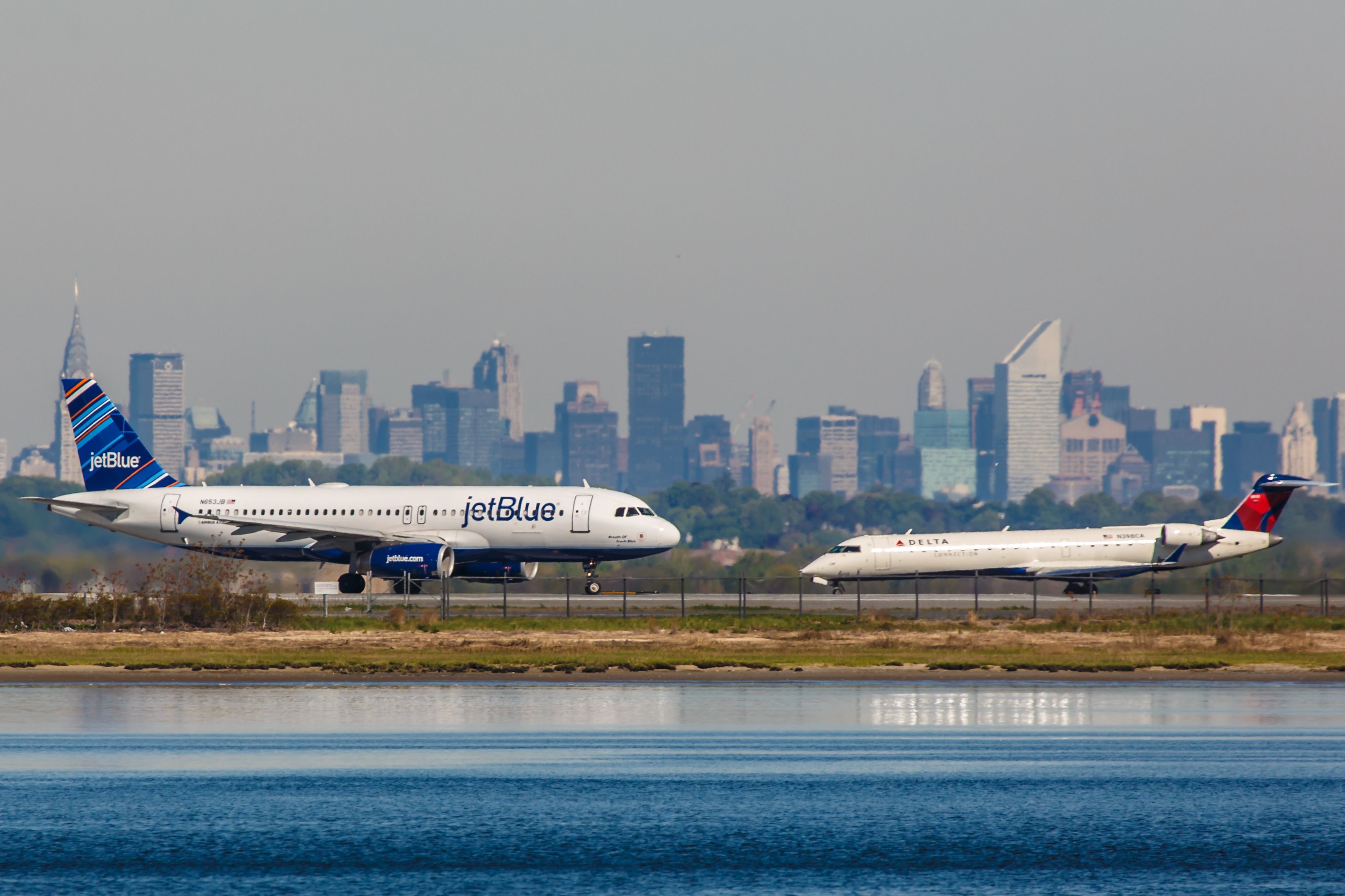 A JetBlue Airbus A320 and a Delta Air Lines Bombardier jet on the runway at New York JFK Airport