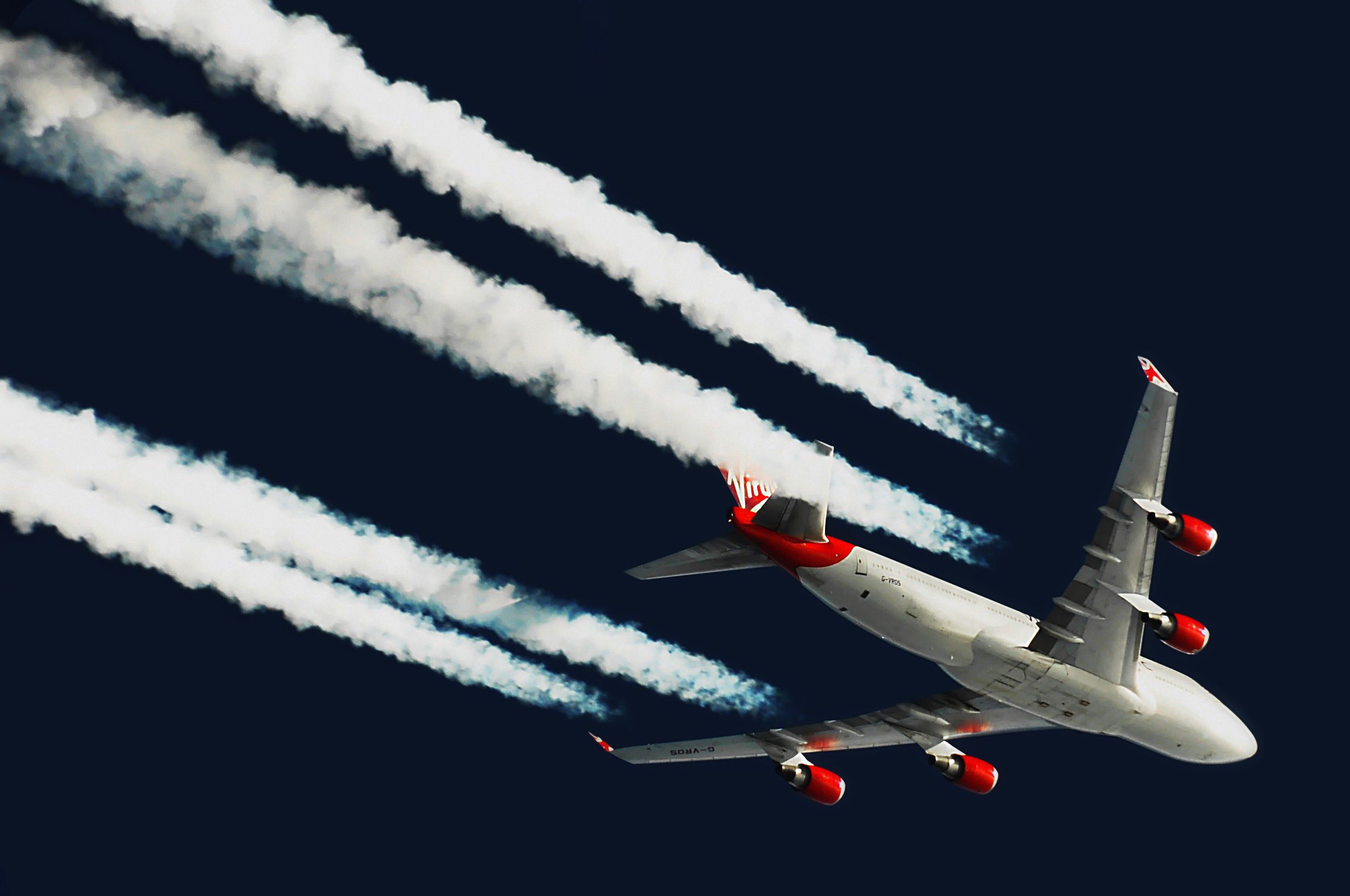 A Virgin Atlantic Boeing 747 mid flight air to air flying over at cruise altitude with contrails above the Atlantic Ocean.