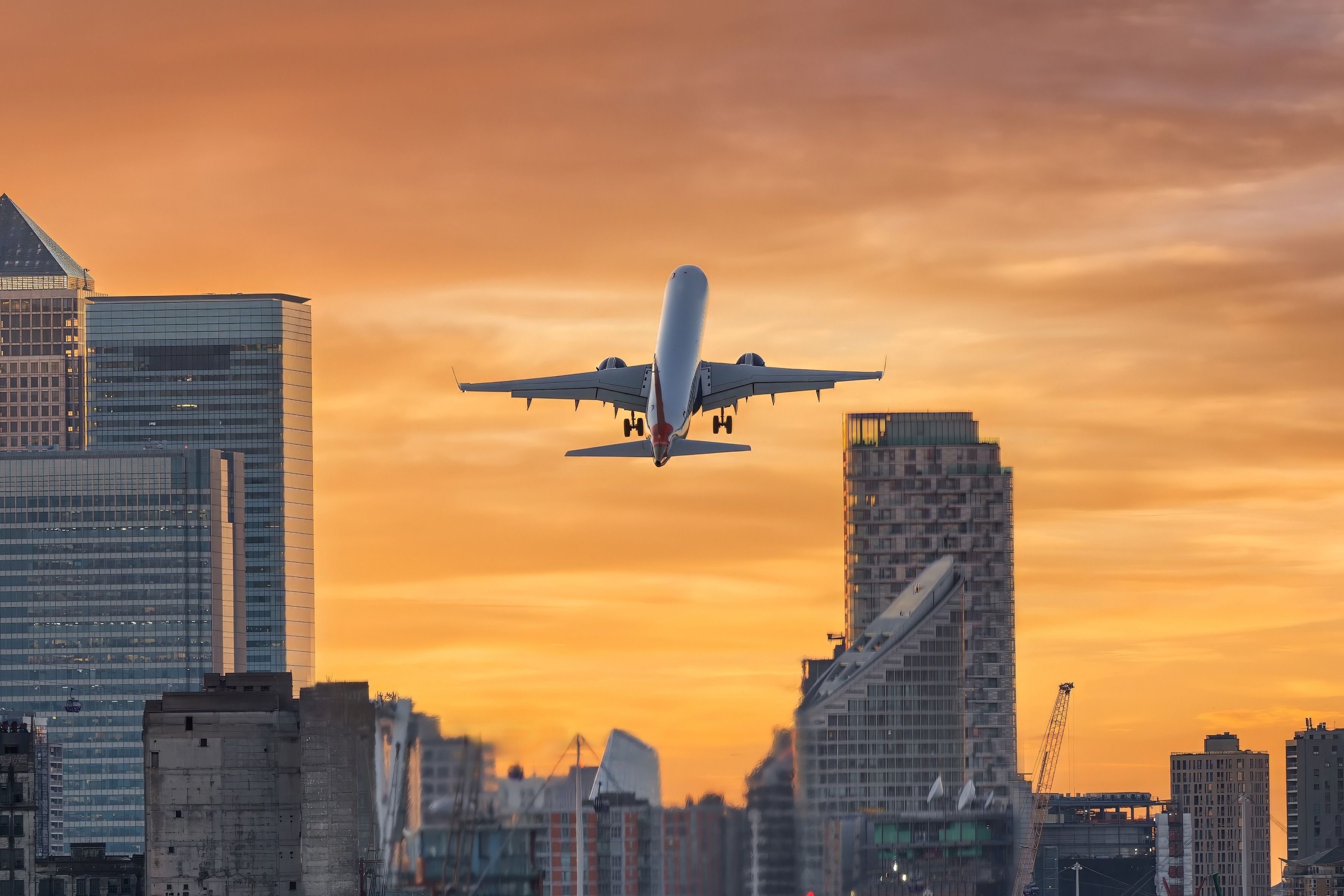 An airplane leaves London City Airport (LCY) at sunset