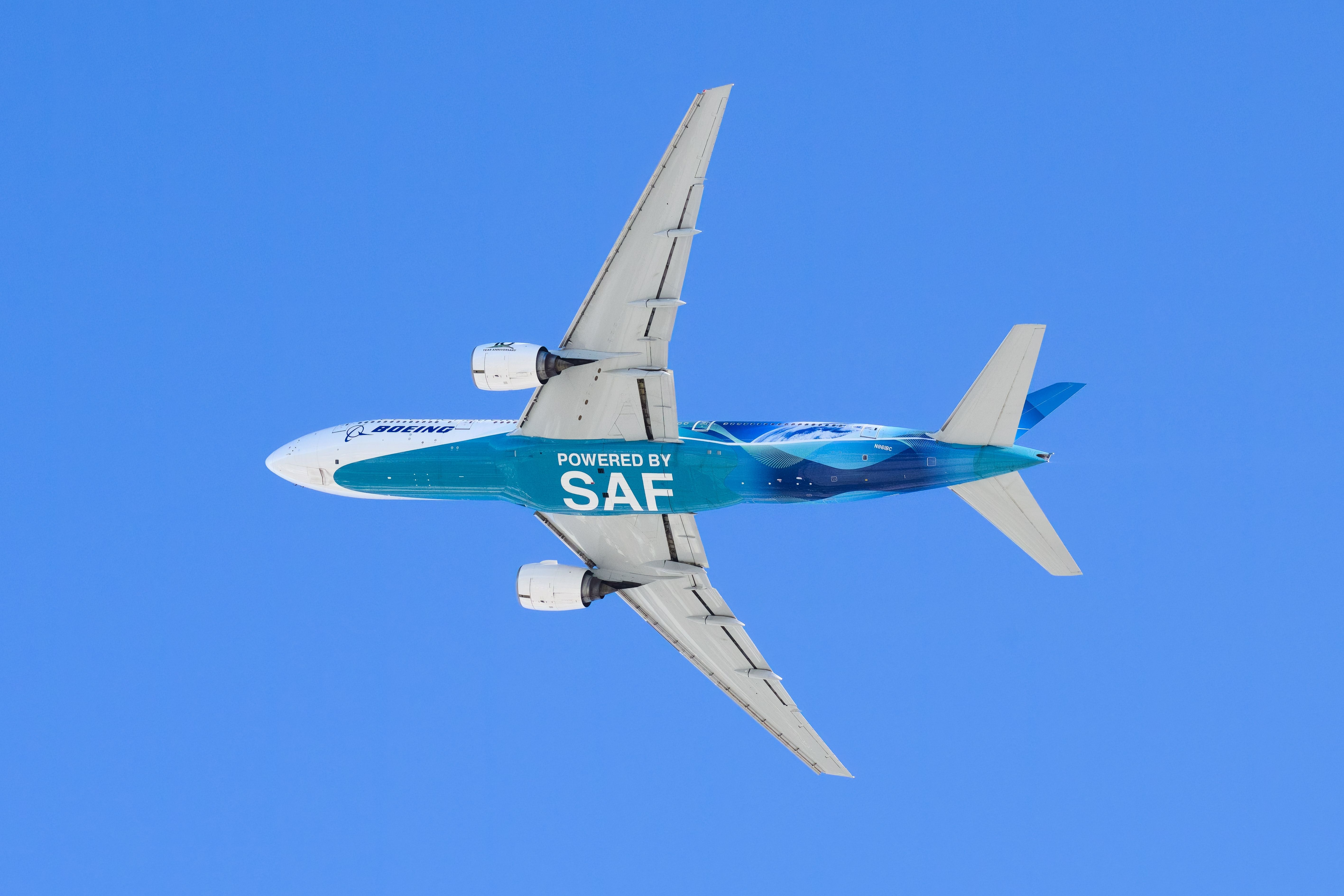 A Boeing 777 underside with the words "Powered by SAF Sustainable Aviation Fuel"