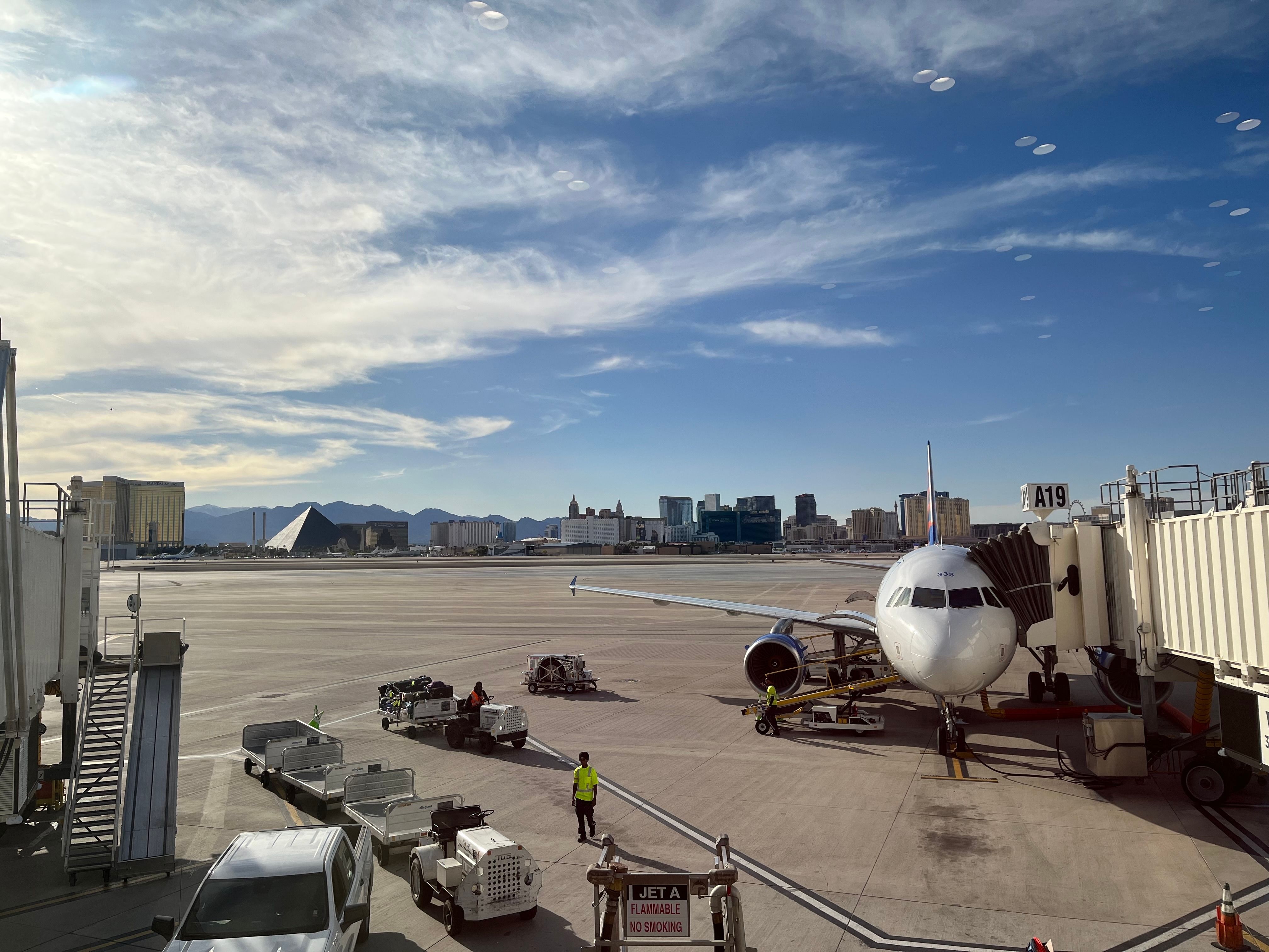 May 7, 2024, Las Vegas, Nevada, USA: At Harry Reid International Airport: Workers move luggage next to an airplane, with the Las Vegas skyline in the background.