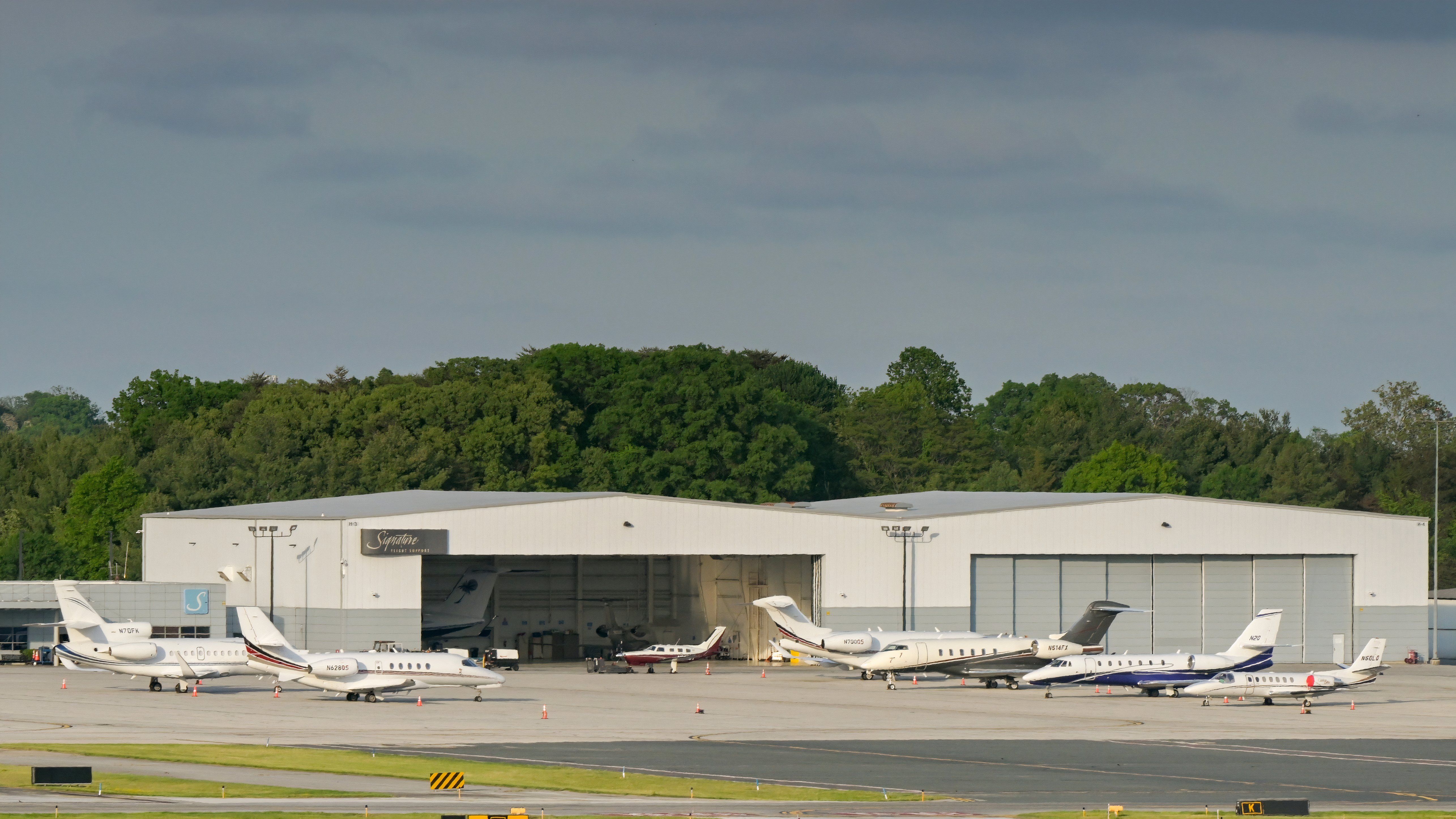 private jets lineup up by hangars