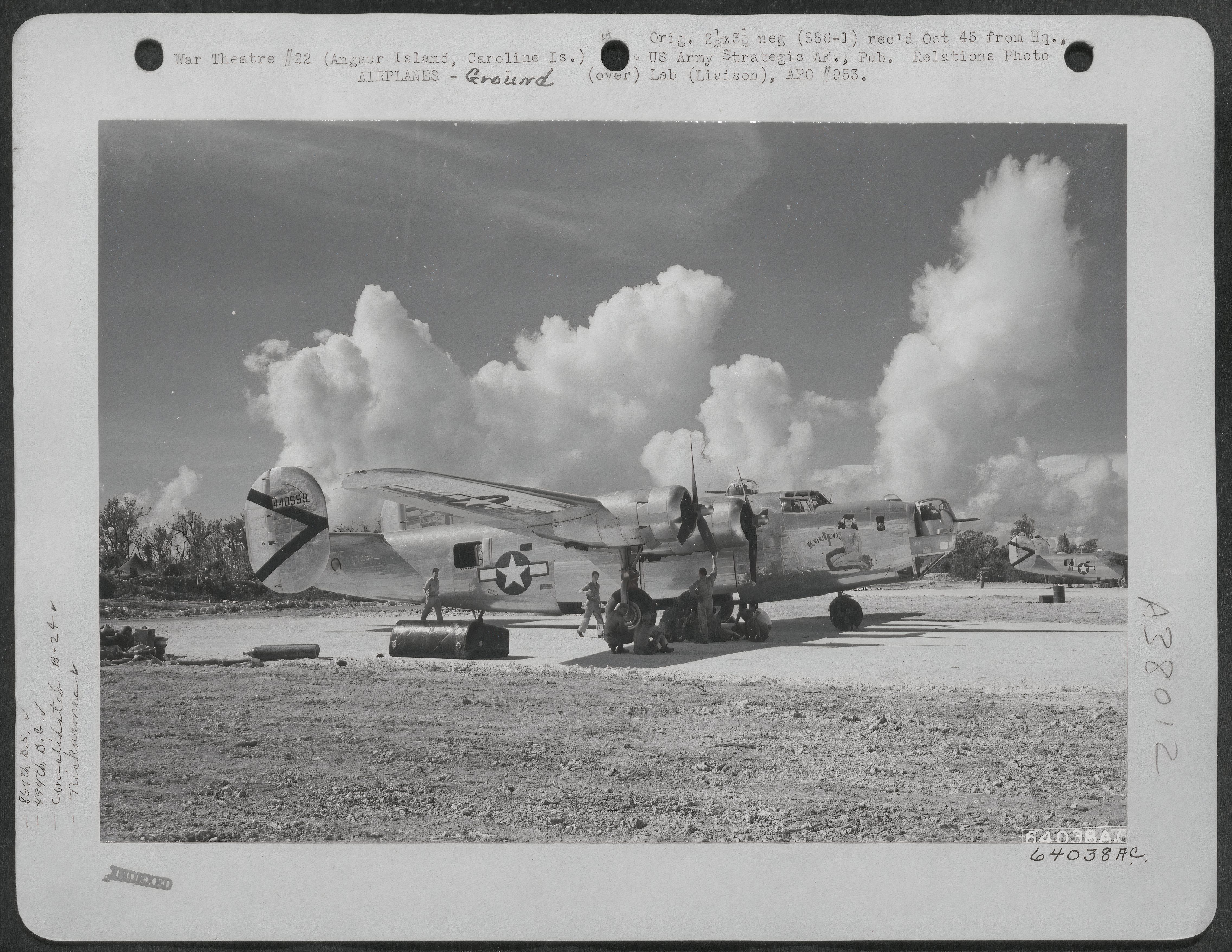 B-24 crew sitting under the wing of their aircraft awaiting orders for a mission.