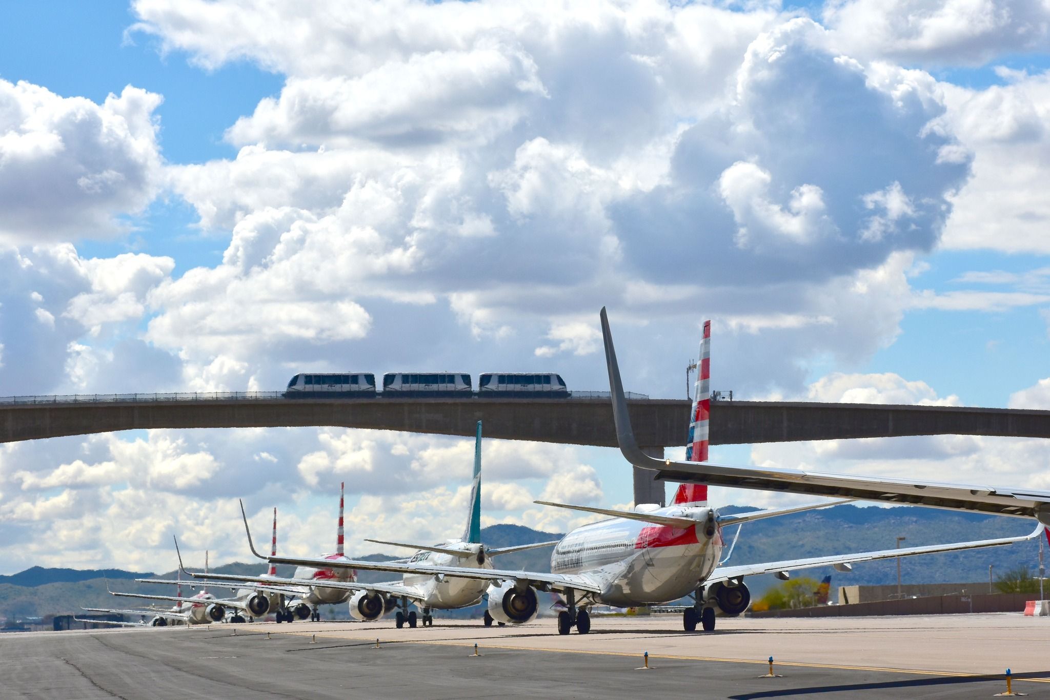 Aircraft lined up under the PHX SkyTrain bridge at Phoenix Sky Harbor International Airport. 