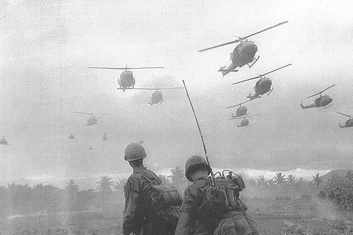 Black and white photo of soldiers of the U.S. Air Cavalry looking up at approaching helicopters.