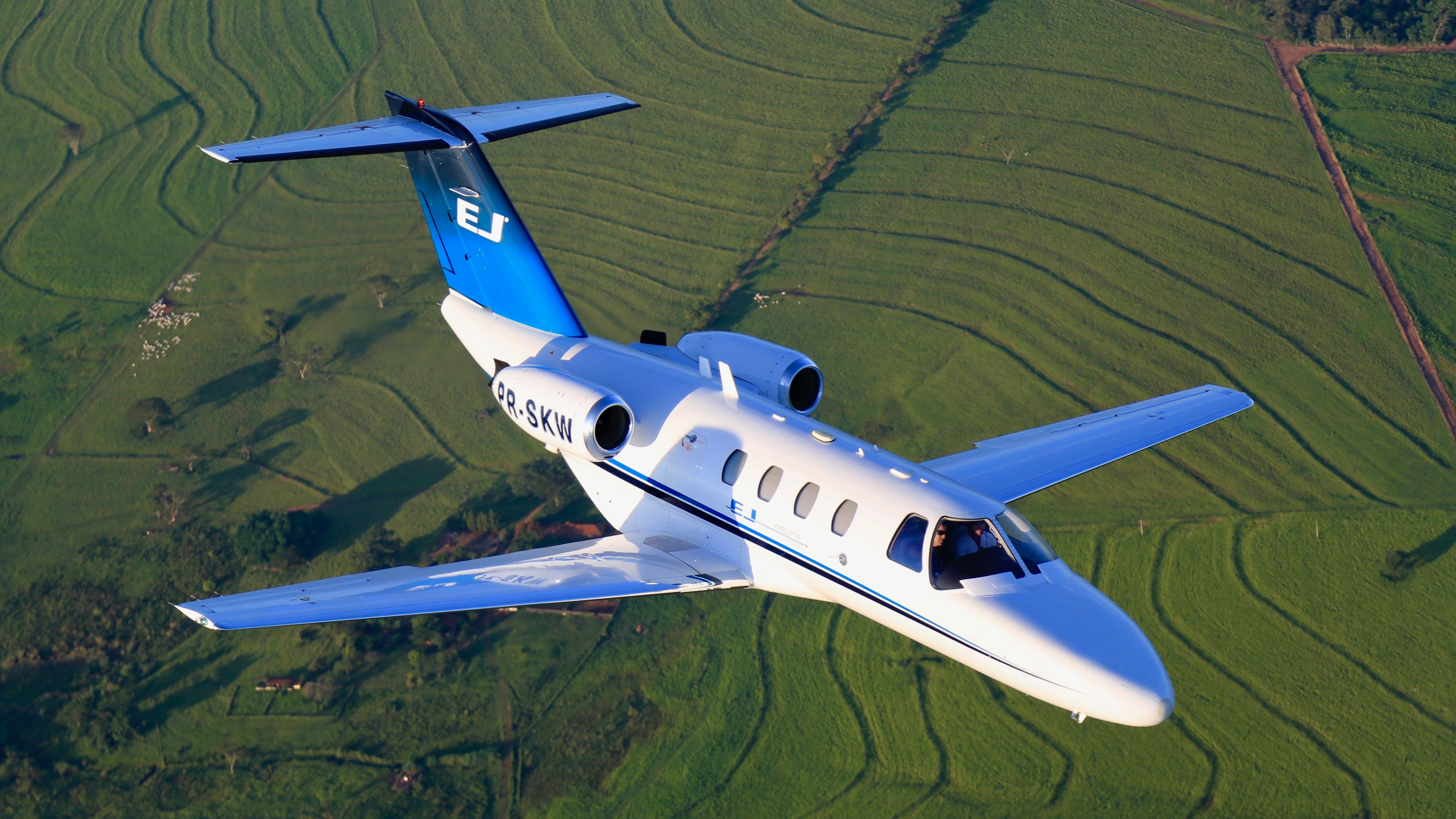 Cessna Citation Jet flying in the sky over fields