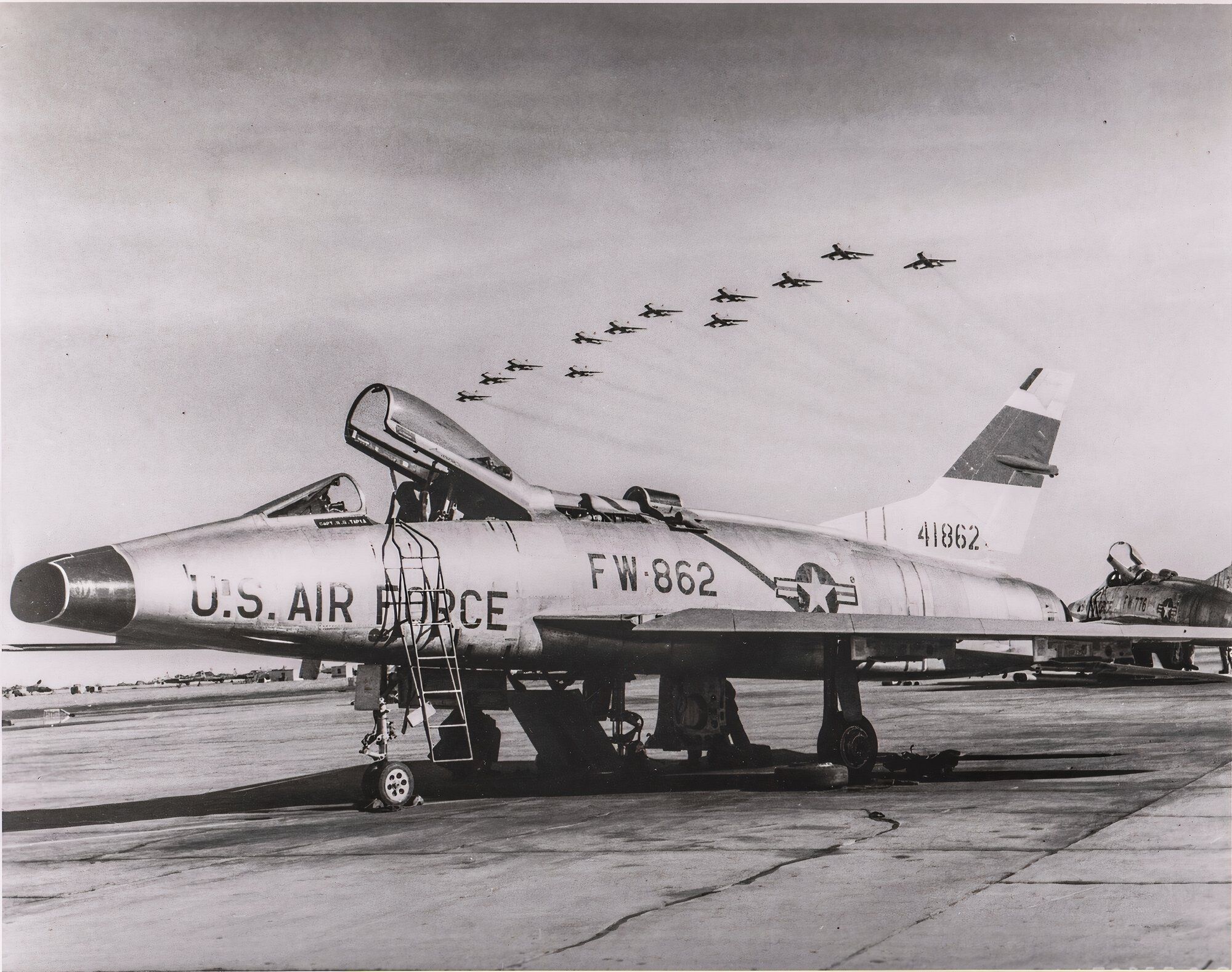 Black and white image of a USAF fighter plane parked at an airbase. 