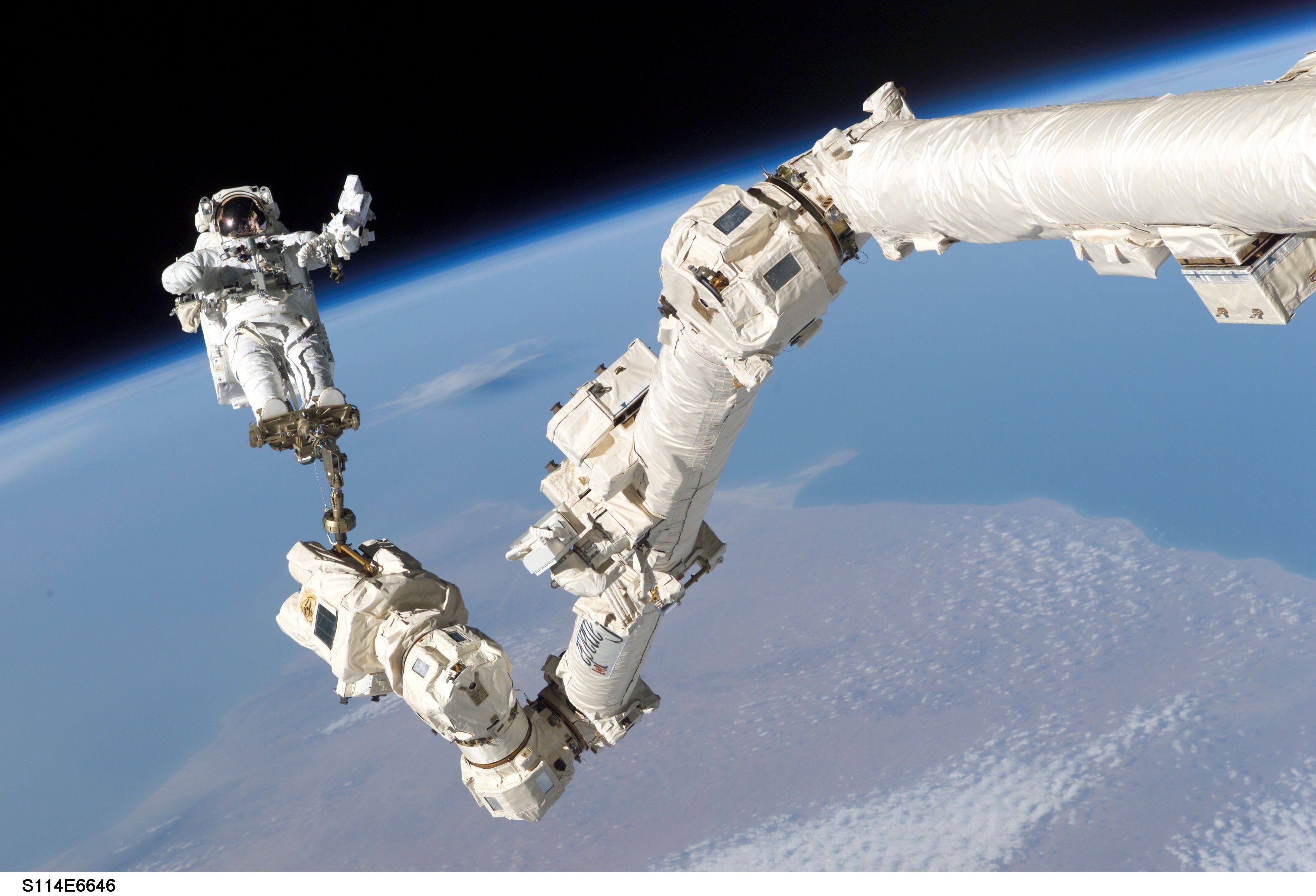 Photo of an astronaut catching a ride on Canadarm2