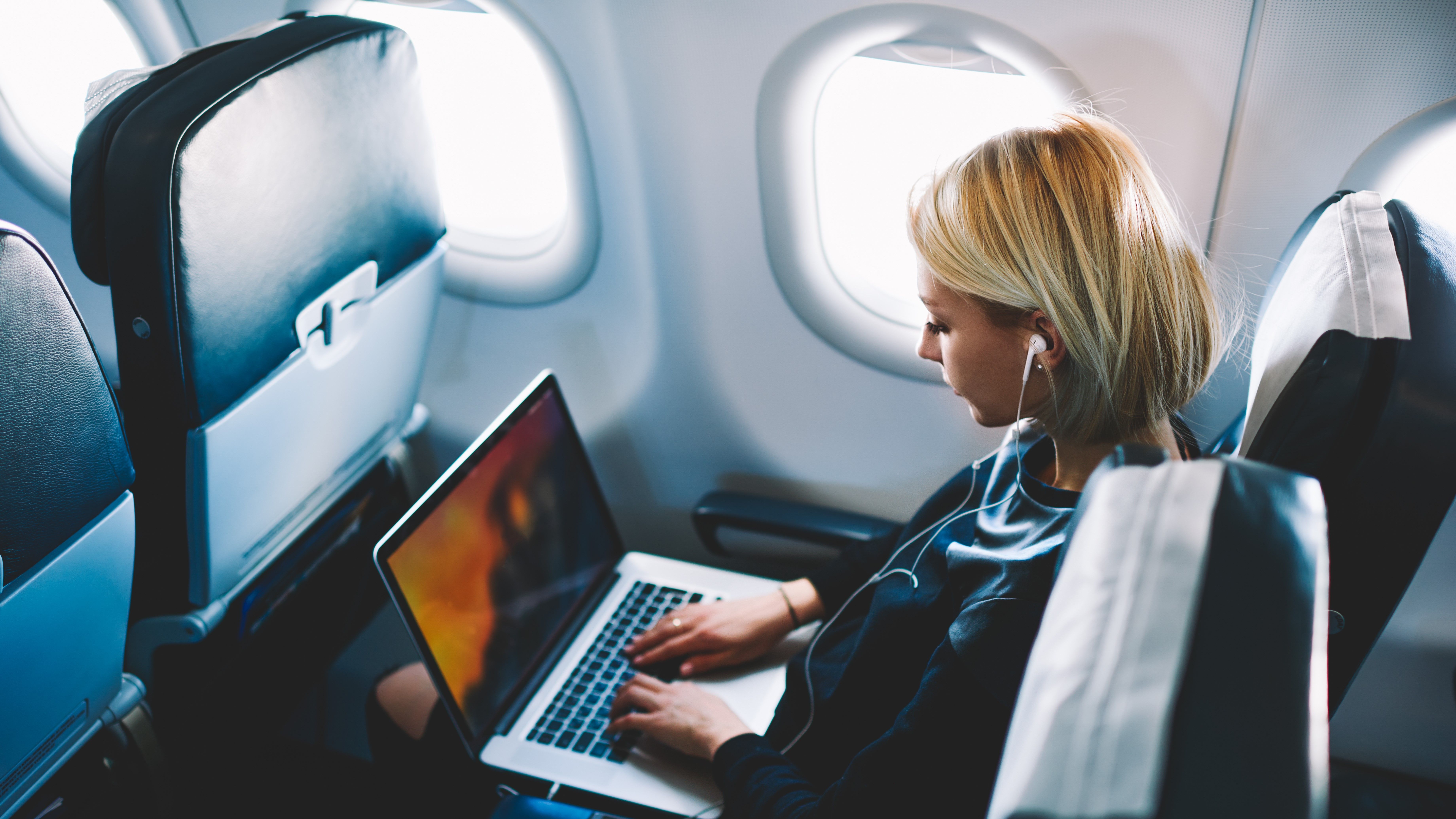 Female Passenger Using A Laptop On A Plane