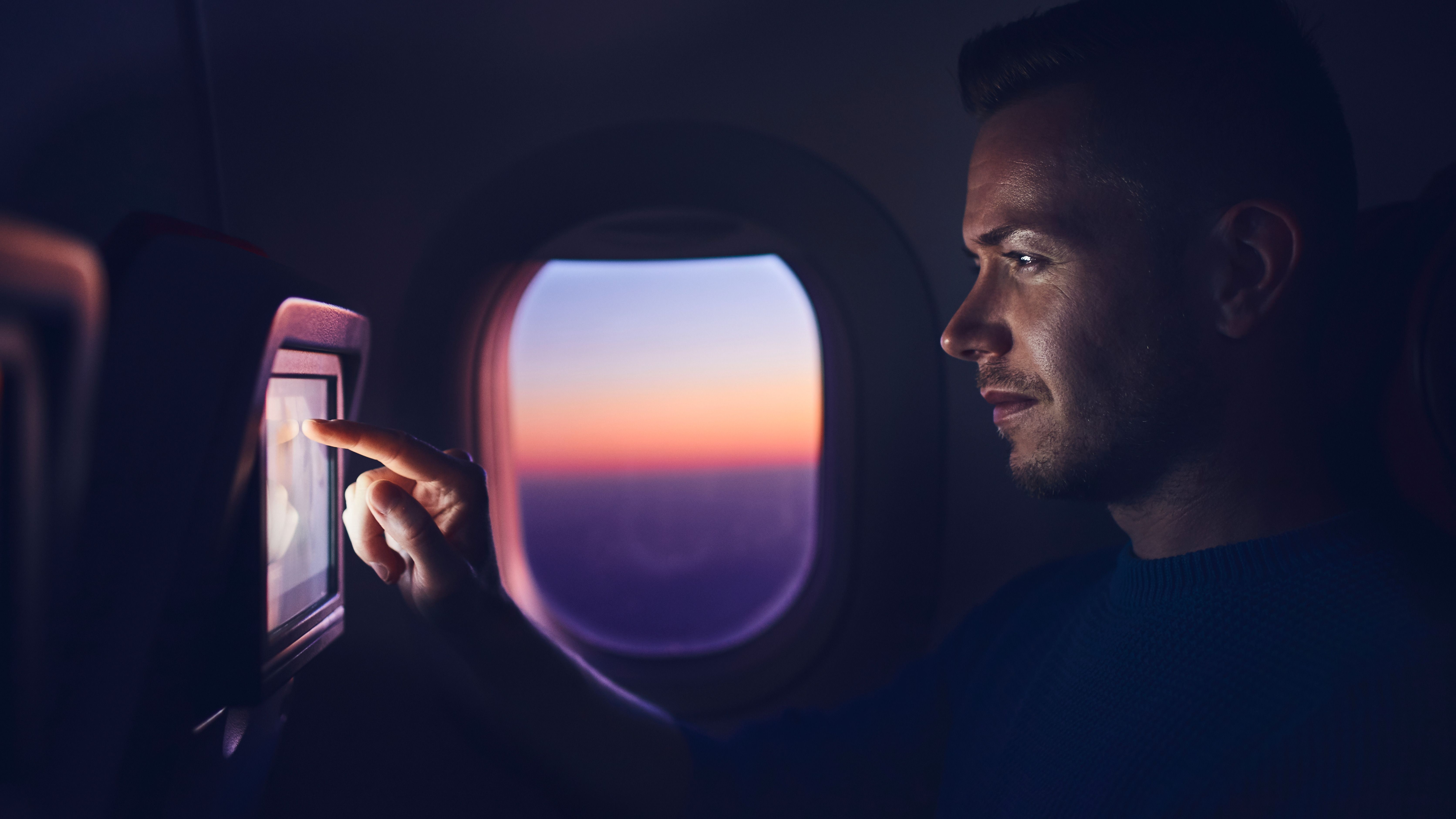 A man watches the inflight entertainment screen