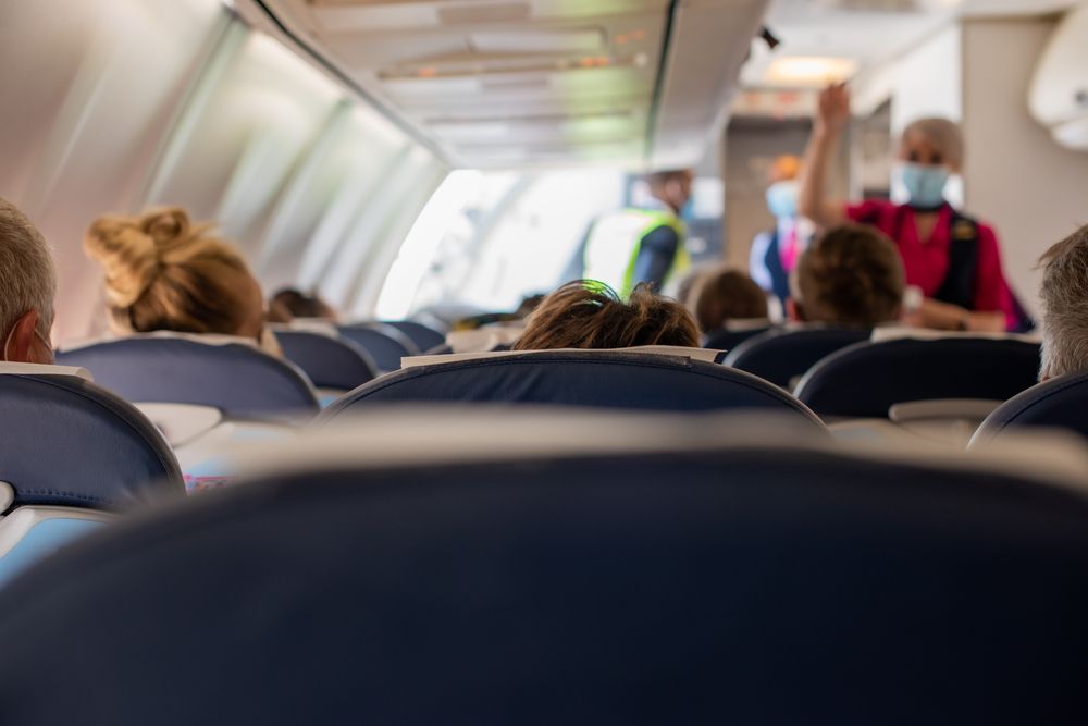  Interior of airplane cabin with flight attendant wearing face mask