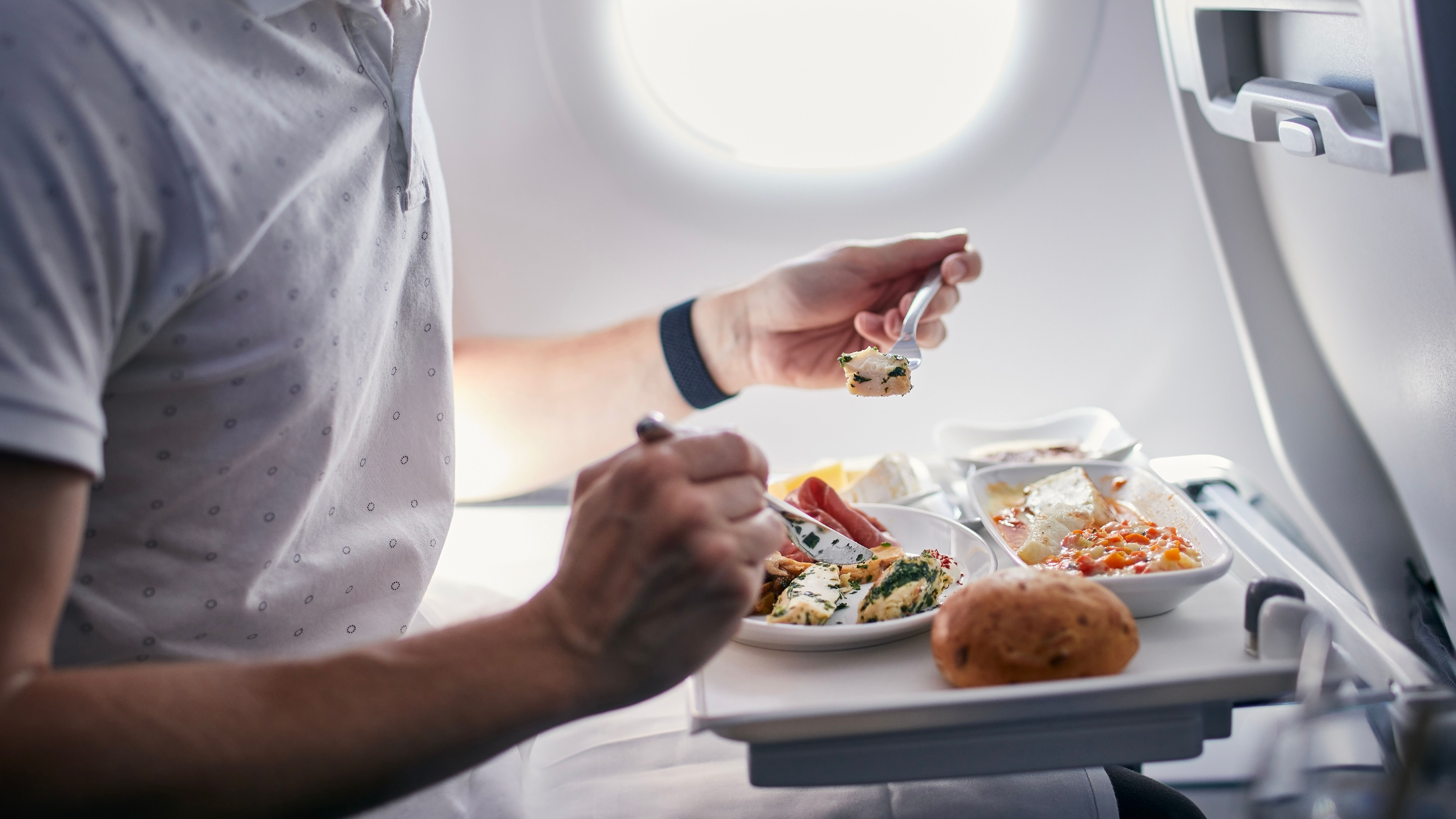 A person eating food on an airplane in-flight meal