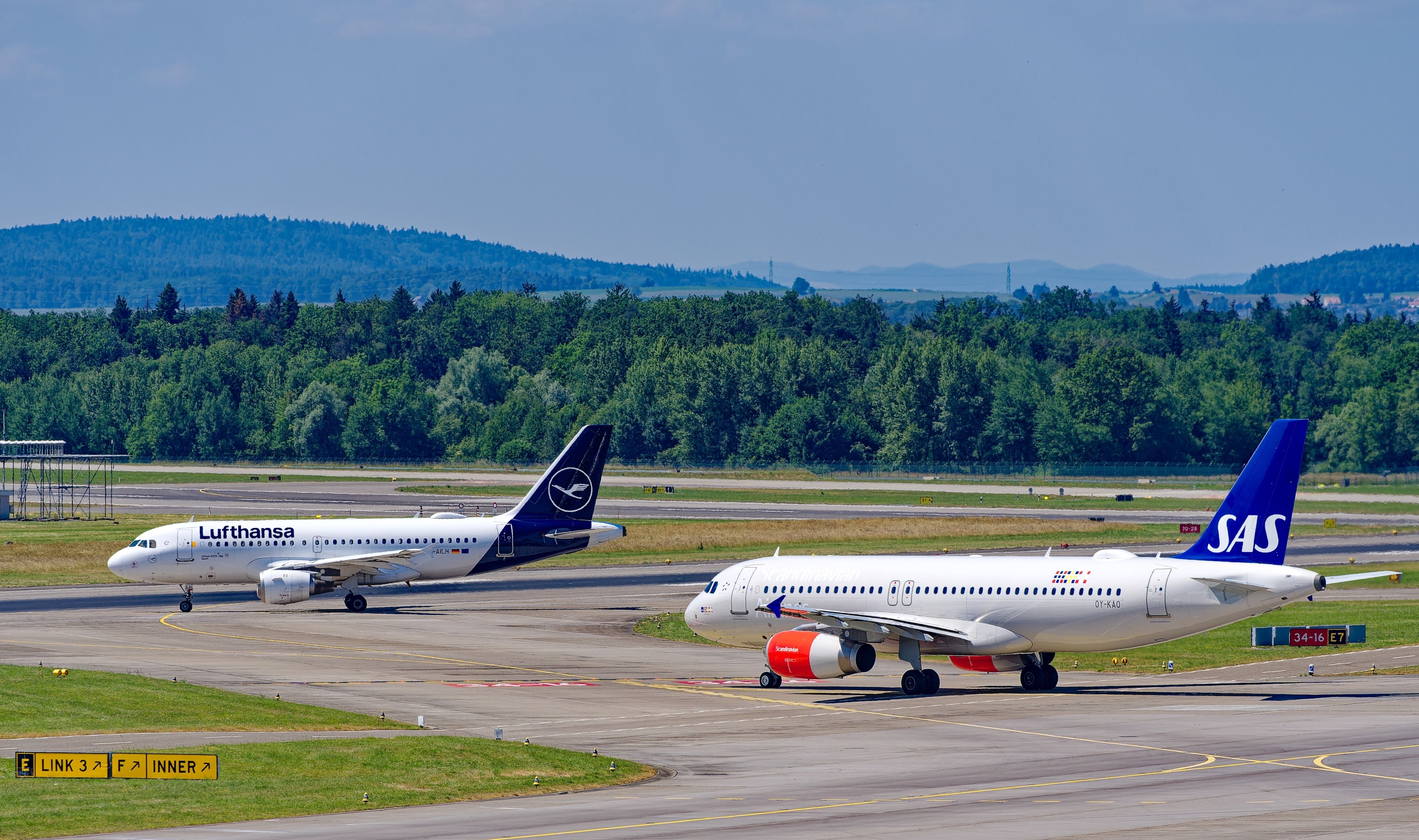 Lufthansa airplane Airbus A319-114 D-AILH and SAS Airbus A320-232 OY-KAO taxiing to runway Zürich Airport on a sunny late spring day