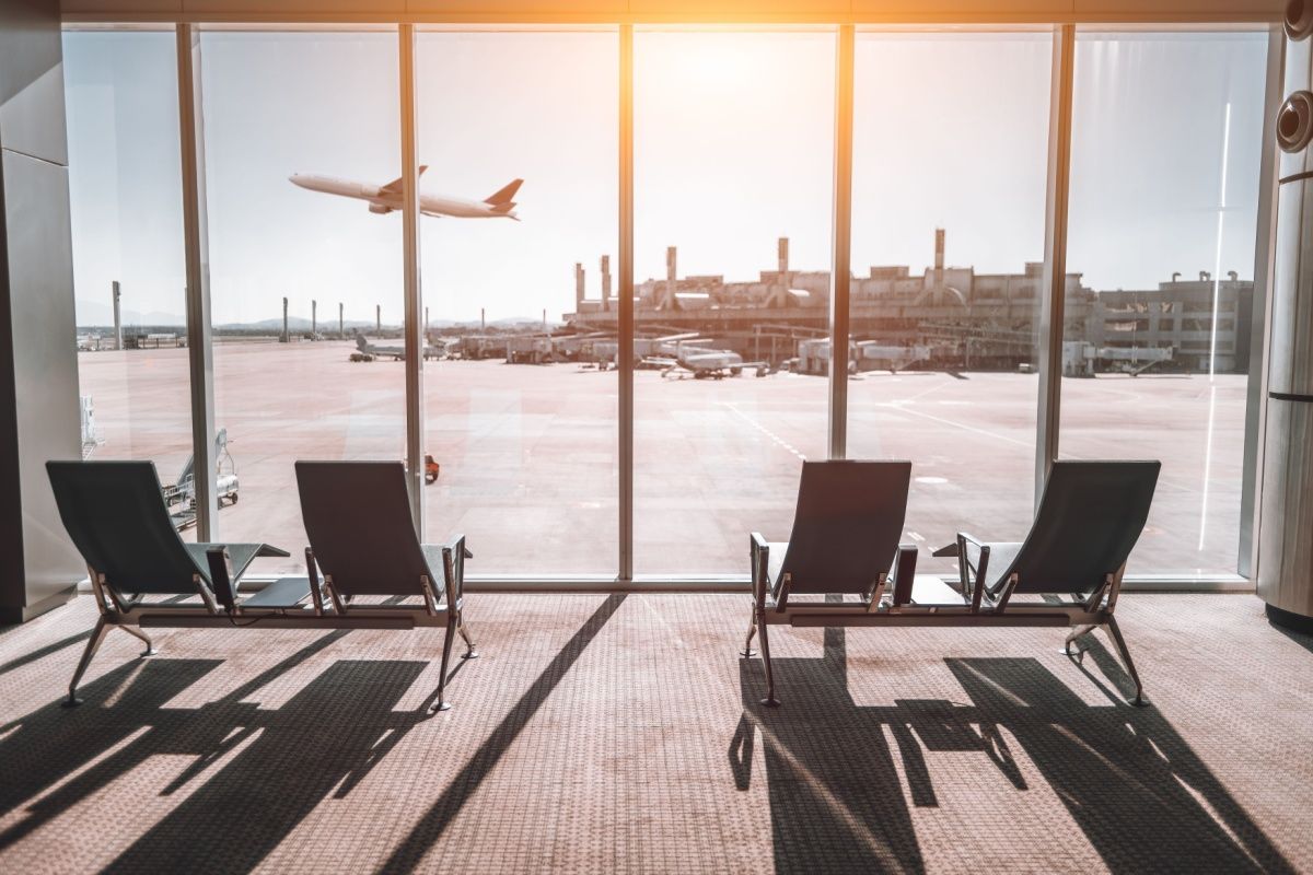 View from an airport terminal window showing chairs facing the runway