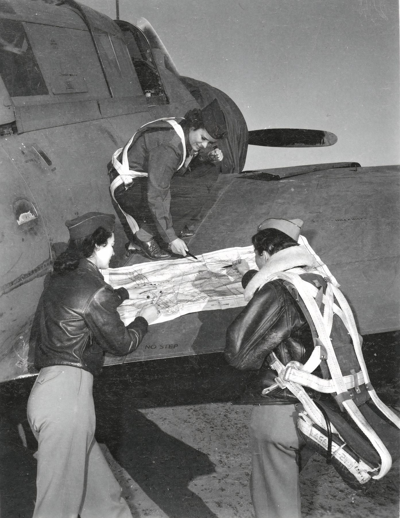 Three WASP pilots on right wing of A-25 checking their flight plan.