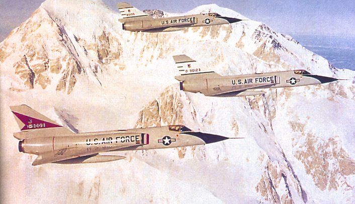 Three F-106s flying in Alaska with a snow covered mountain in the background. 