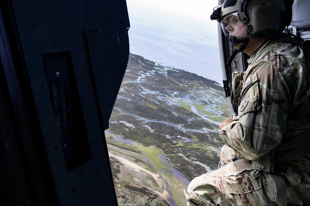 Helicopter crew member surveying flooded area.