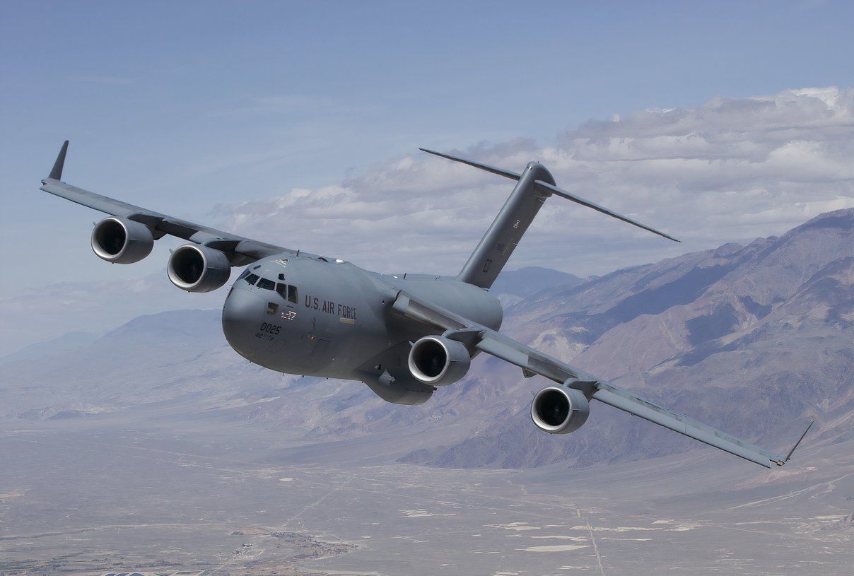 C-17 flying against a mountainous background.