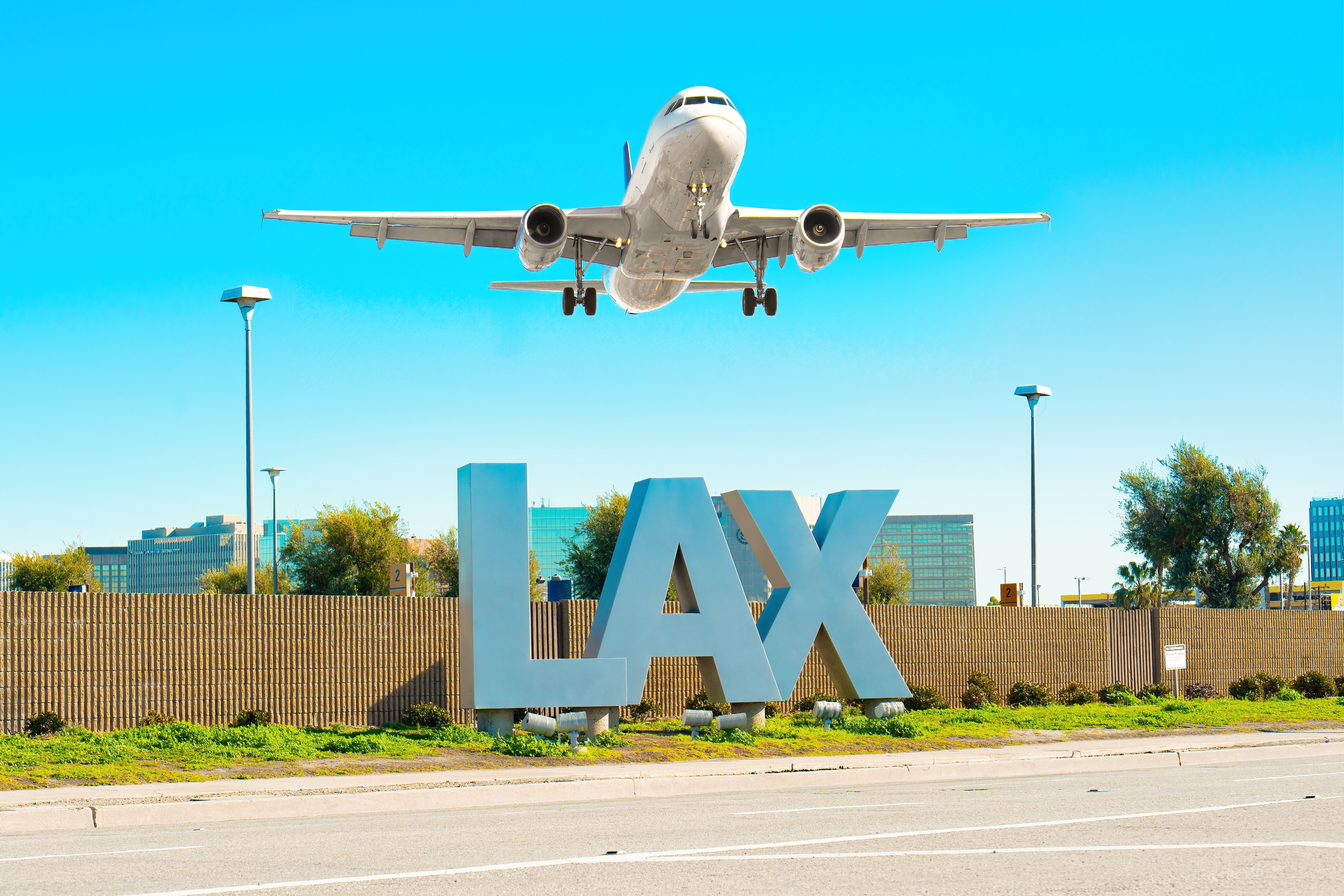 A plane flying low over the LAX sign