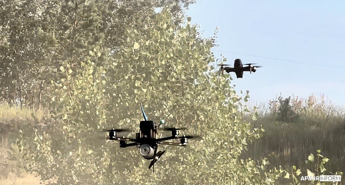 Photo of two drones flying in a forested area