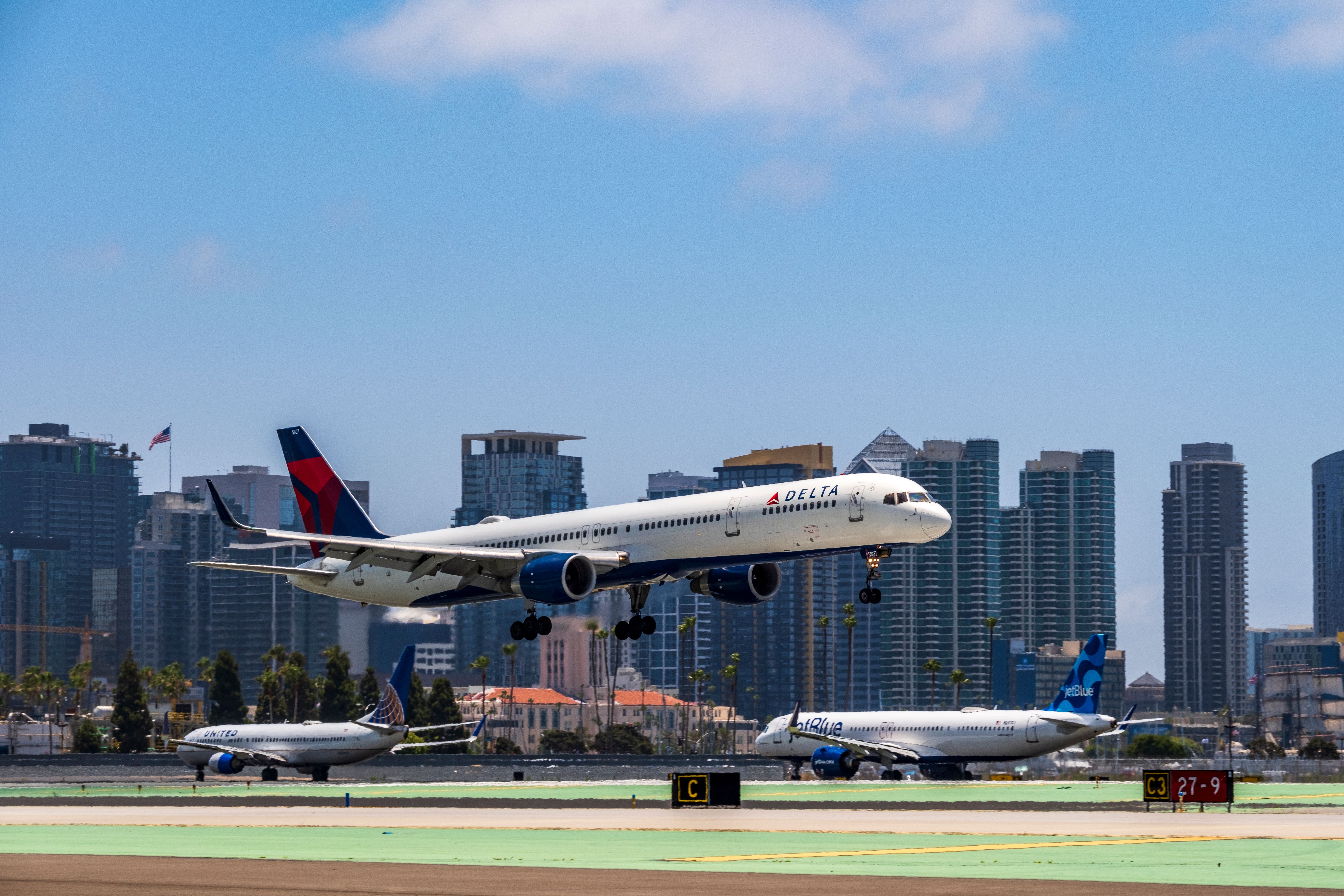 A Delta Plane taking off in front of United and Jetblue planes at San Diego International Airport