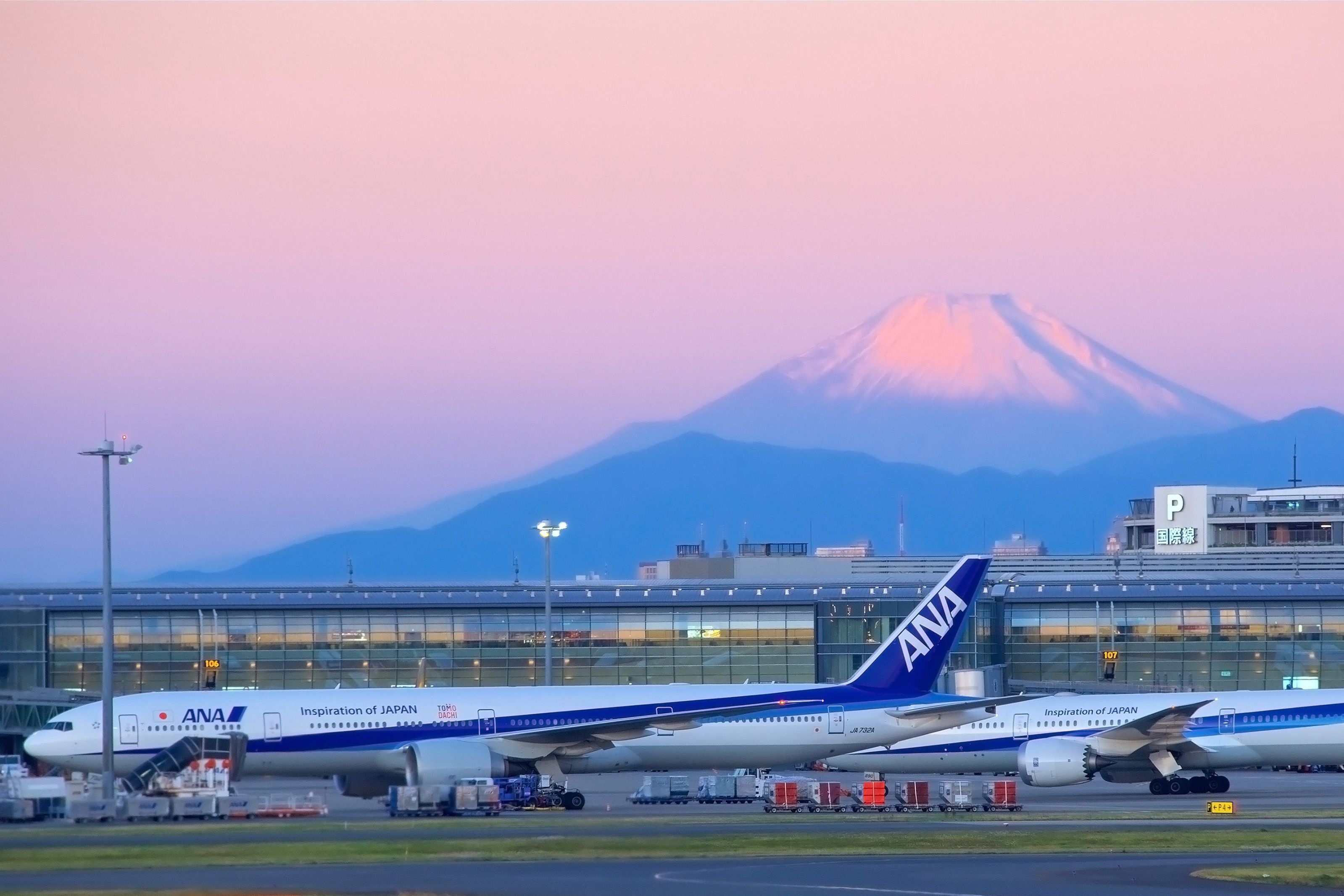 All Nippon Airlines aircraft parked at Tokyo's Haneda Airport in front of Mount Fuji at sunrise