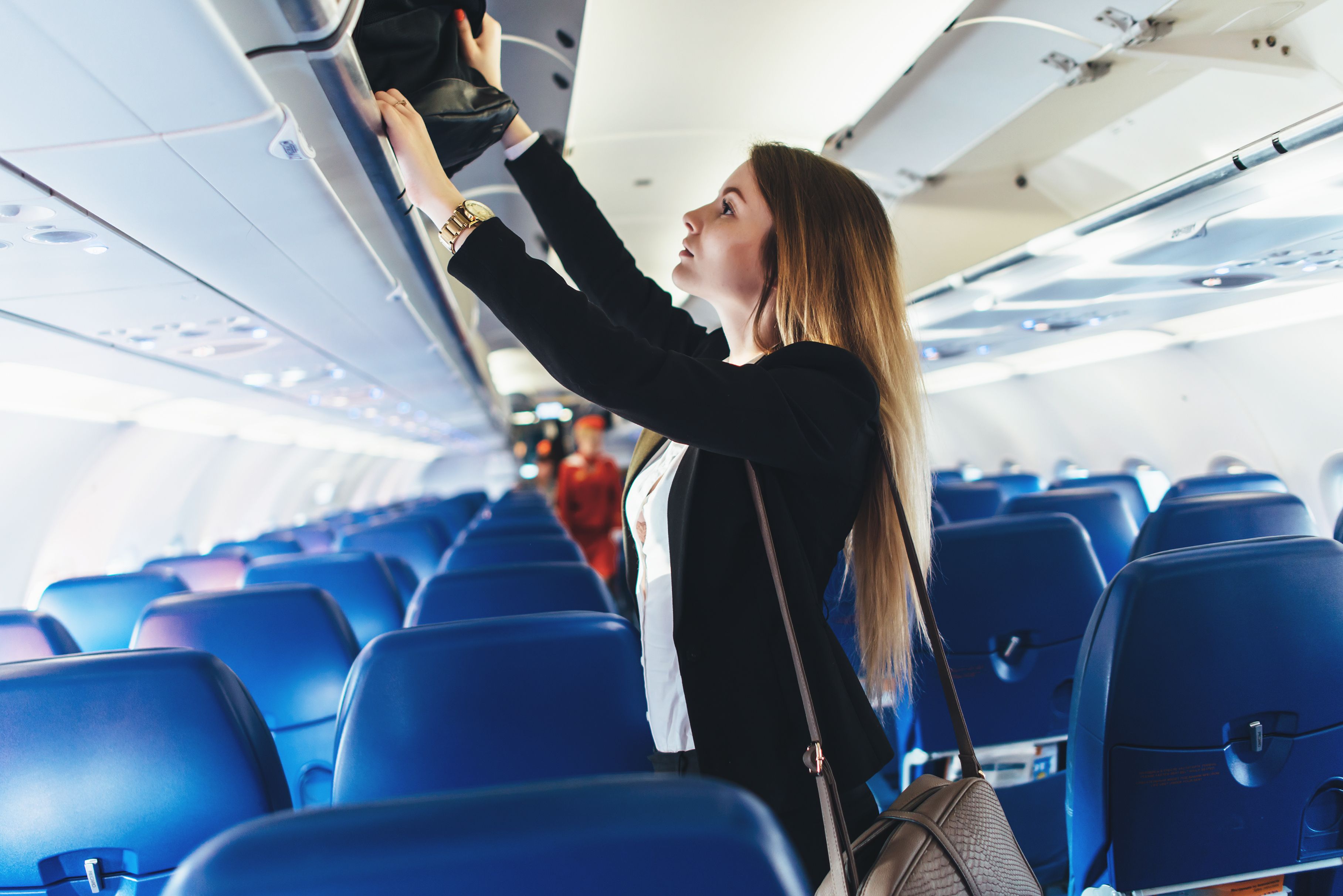 Woman stowing carryon baggage in overhead bin