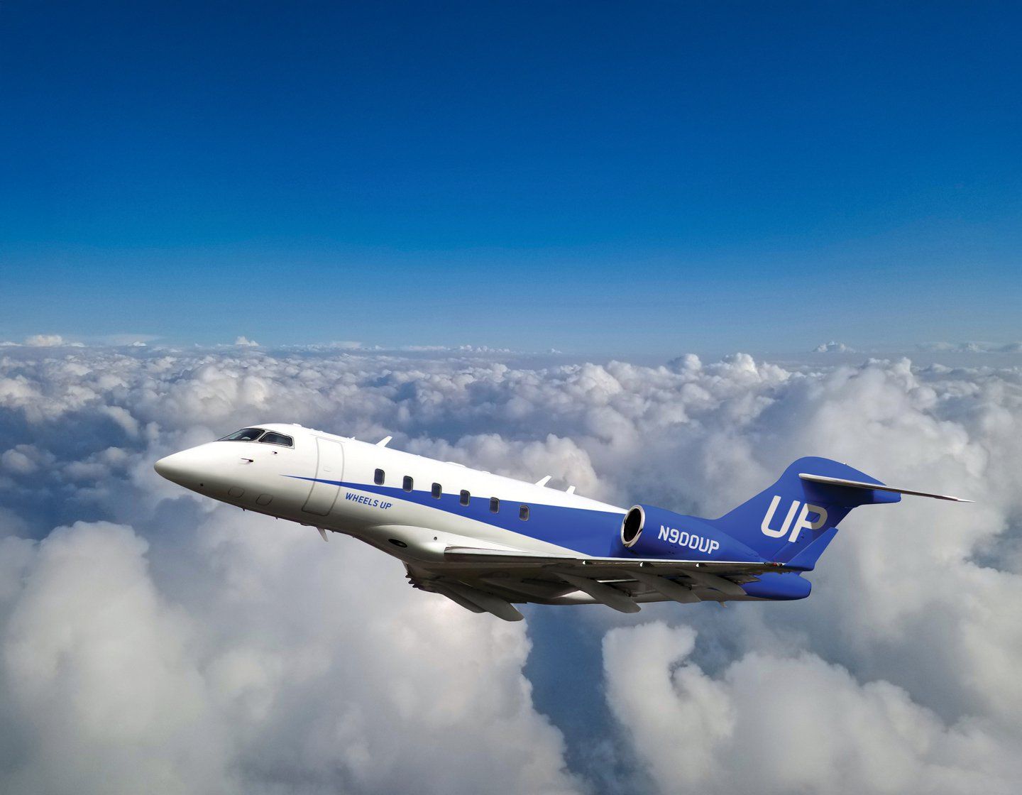 Wheels Up Challenger aircraft climbing above the clouds.