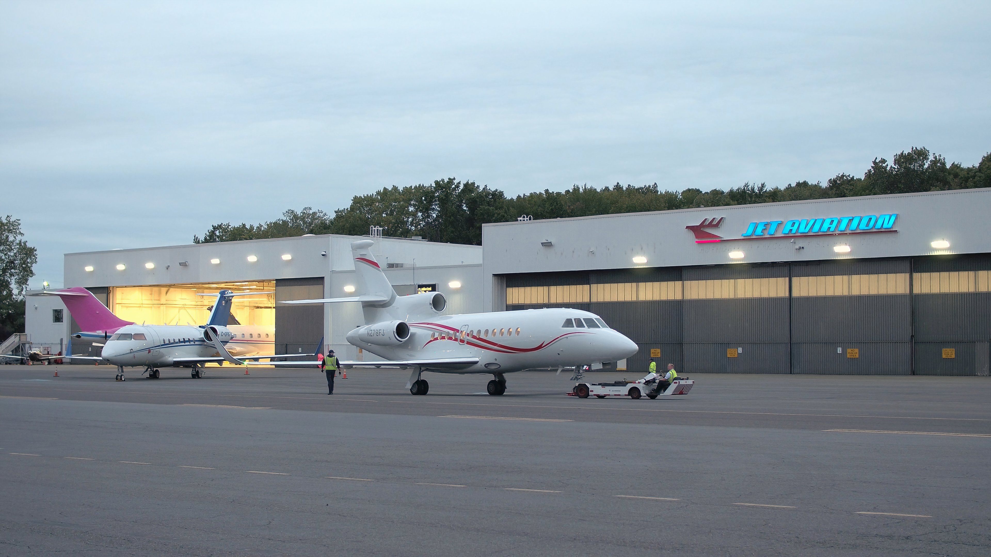 Line technicians working in Teterboro Airport, operating aircraft towing vehicle and parking airplane in the hangar. 