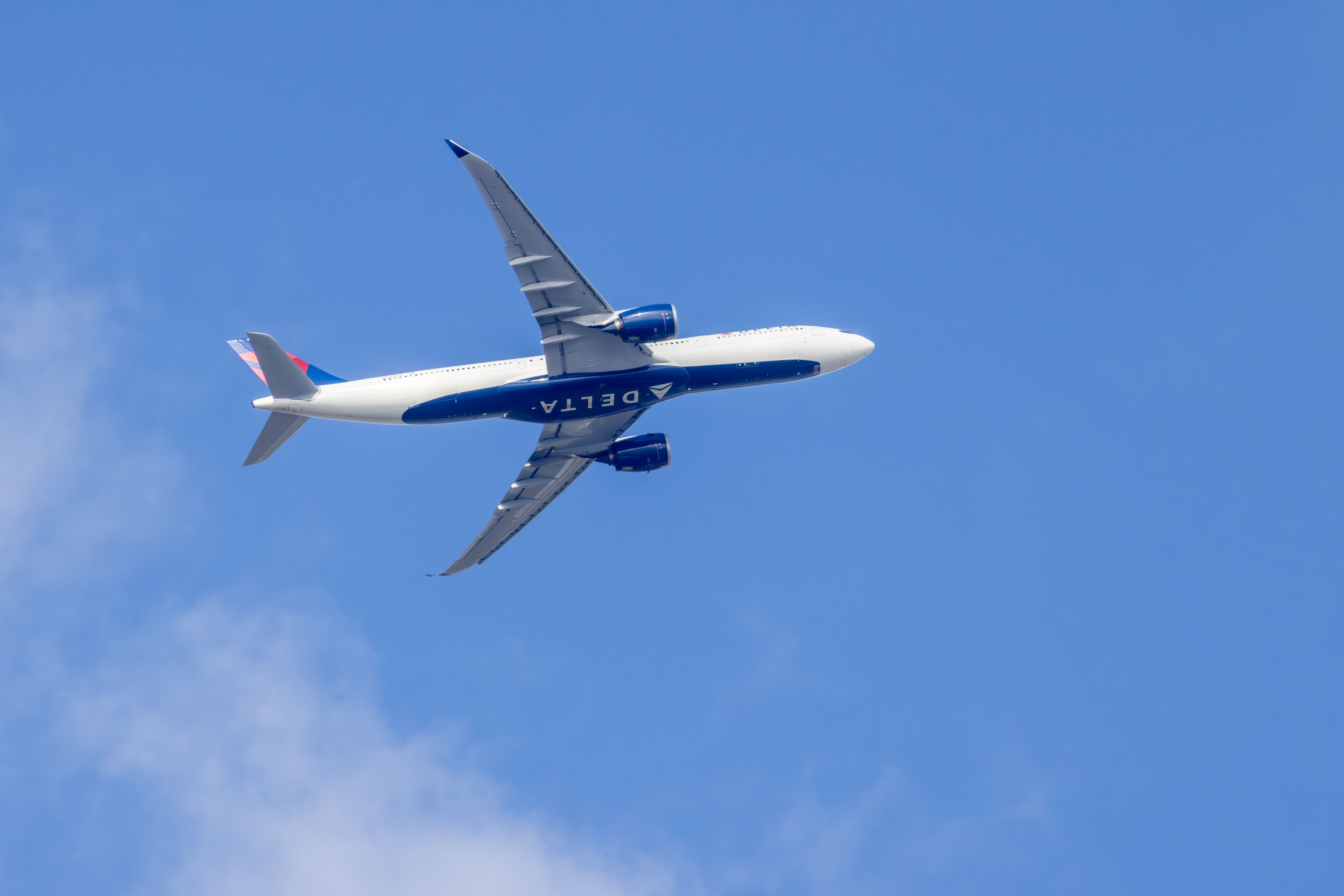 Delta Air Lines Airbus A330 بانکداری در هنگام پرواز در یک آسمان آبی با برخی از ابرها