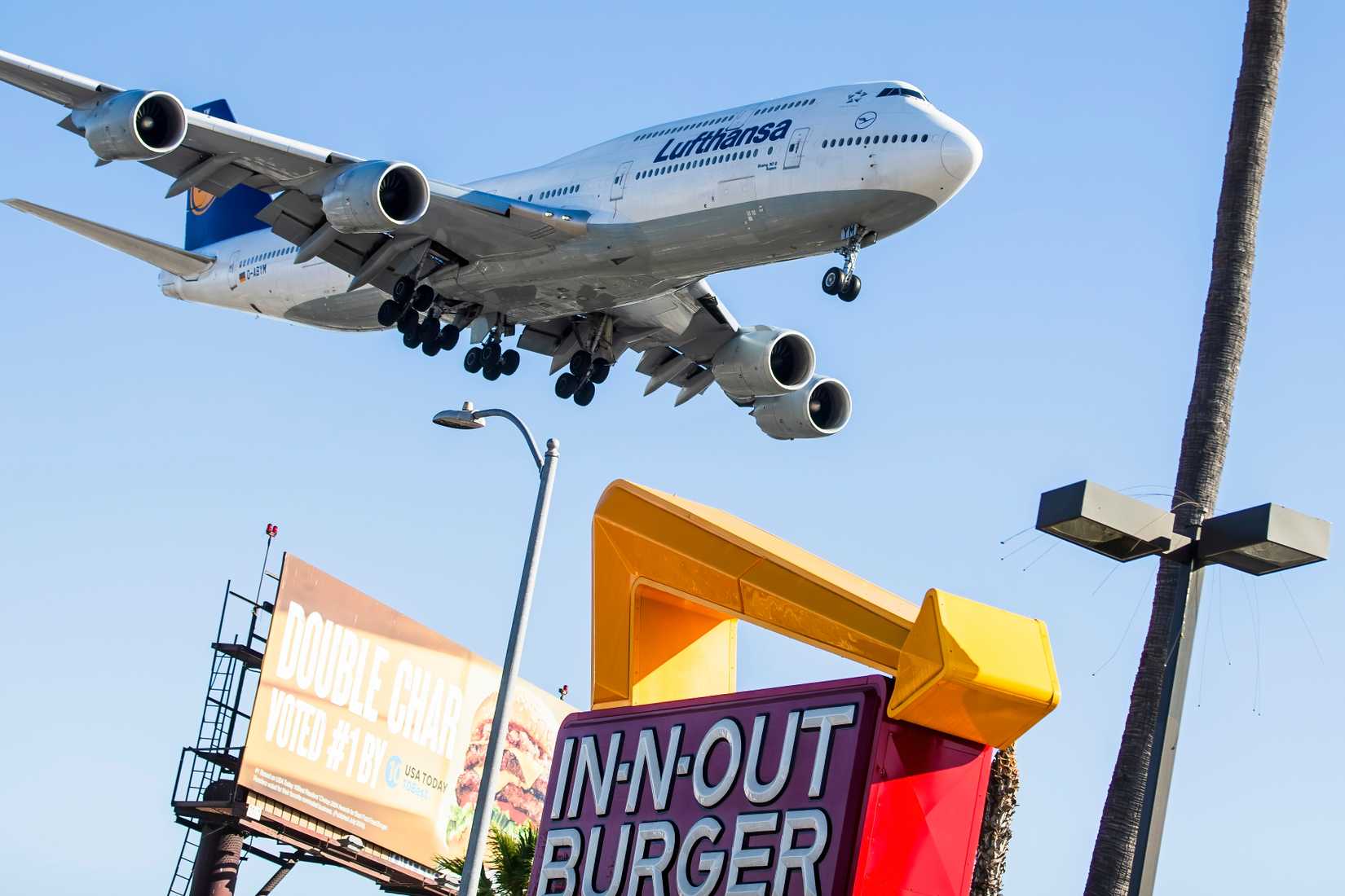 Boeing 747-8. A Lufthansa Boeing 747 flies over an In-N-Out Burger restaurant