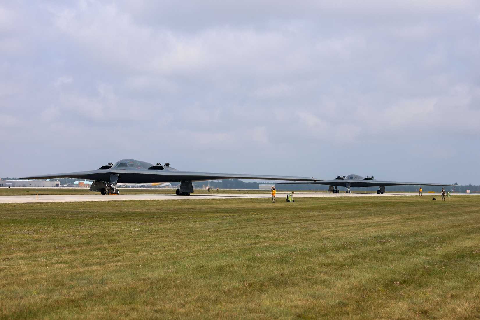 Two U.S. Air Force B-2 Spirit stealth bombers assigned to the 131st Bomb Wing, Missouri Air National Guard, come to a halt before performing an aircrew changeover at Oscoda-Wurtsmith Airport, Michigan, Aug. 5, 2025.